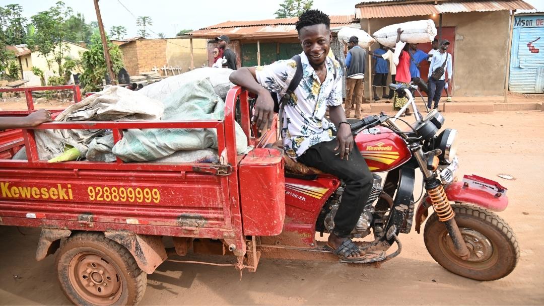 A man smiles with his motorized bike, which helps support reading club activities.