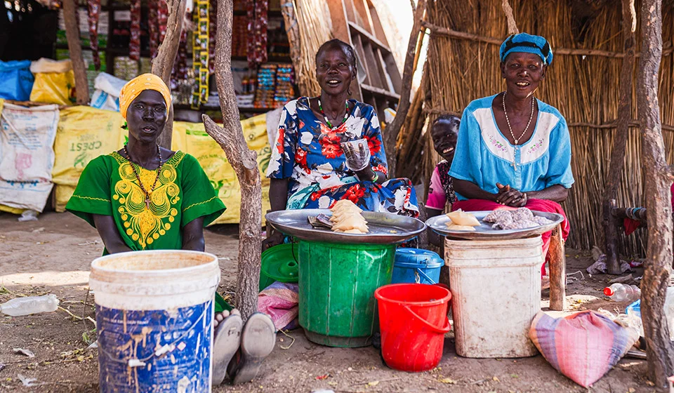 feed-2-three-women-sitting-at-a-market.webp