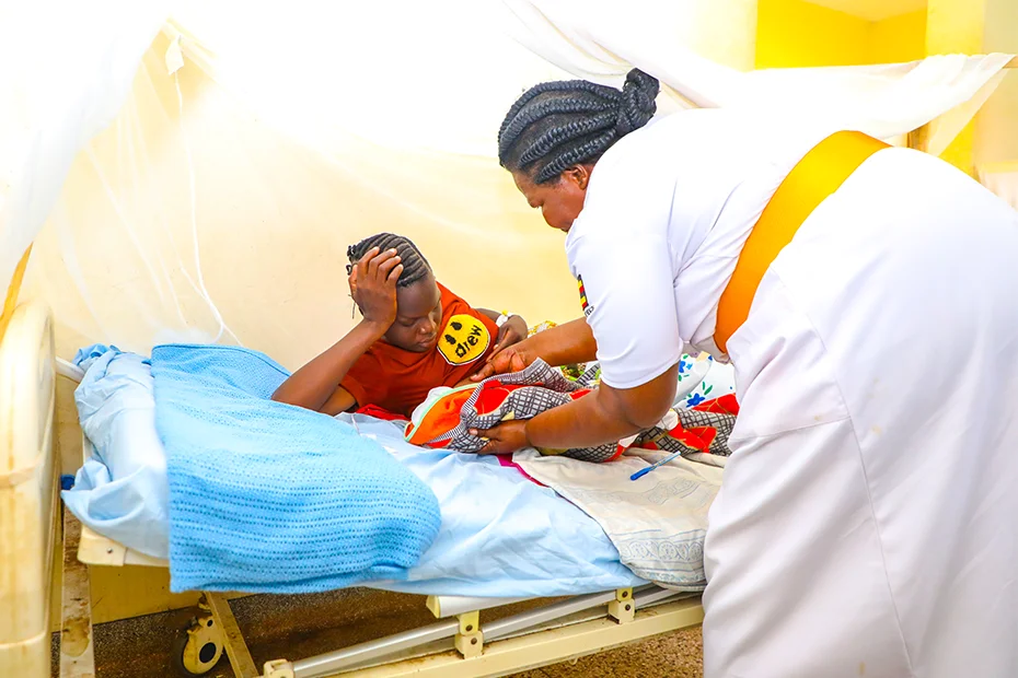 A mother is nursing her newborn baby with the assistance of a nurse.