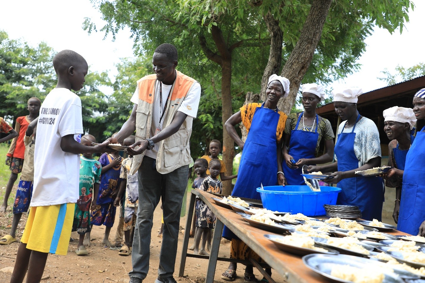 World vision staff distribute school meals at a refugee camp.