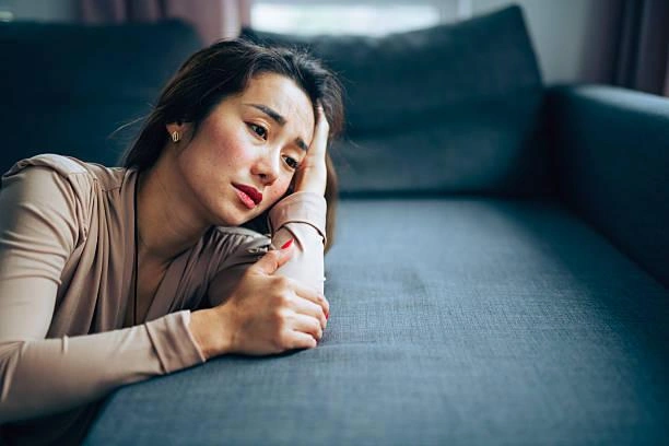 Woman kneeling next to a green couch looking sad and stressed