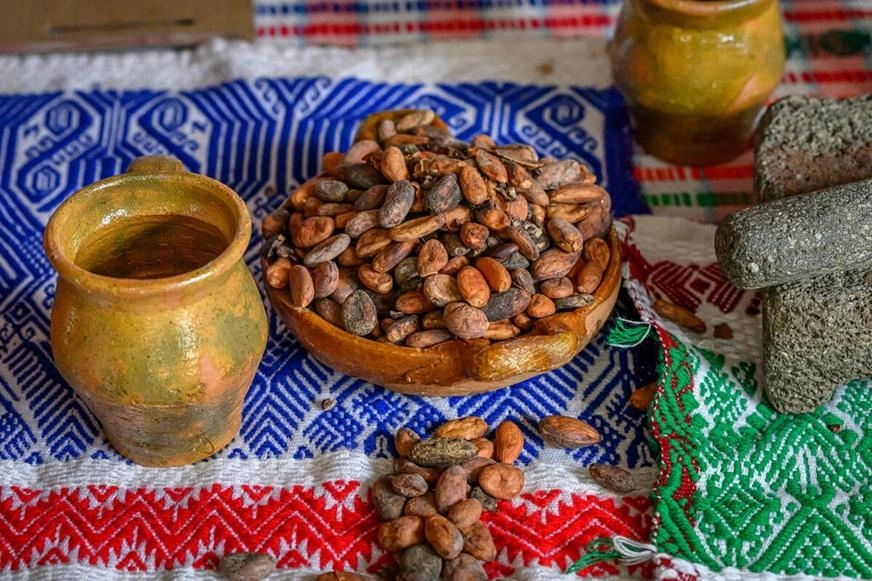 A bowl of cacao beans sits on a table with a jar and mortar and pestle. (Guatemala, 2024)