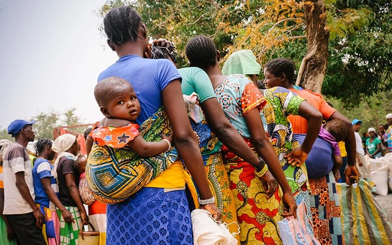 Mothers from the Central African Republic line up for relief goods, some carrying babies tied to their backs with slings.