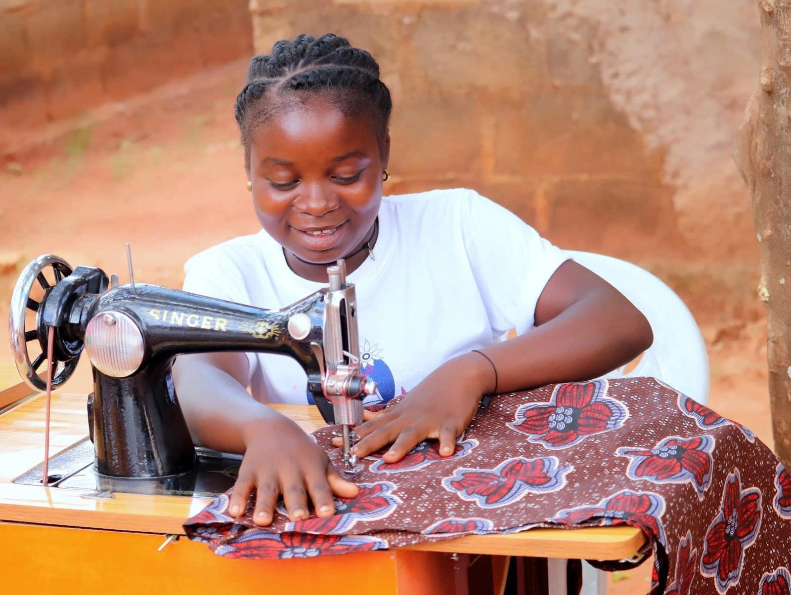 A young girl smiles as she uses a sewing machine.
