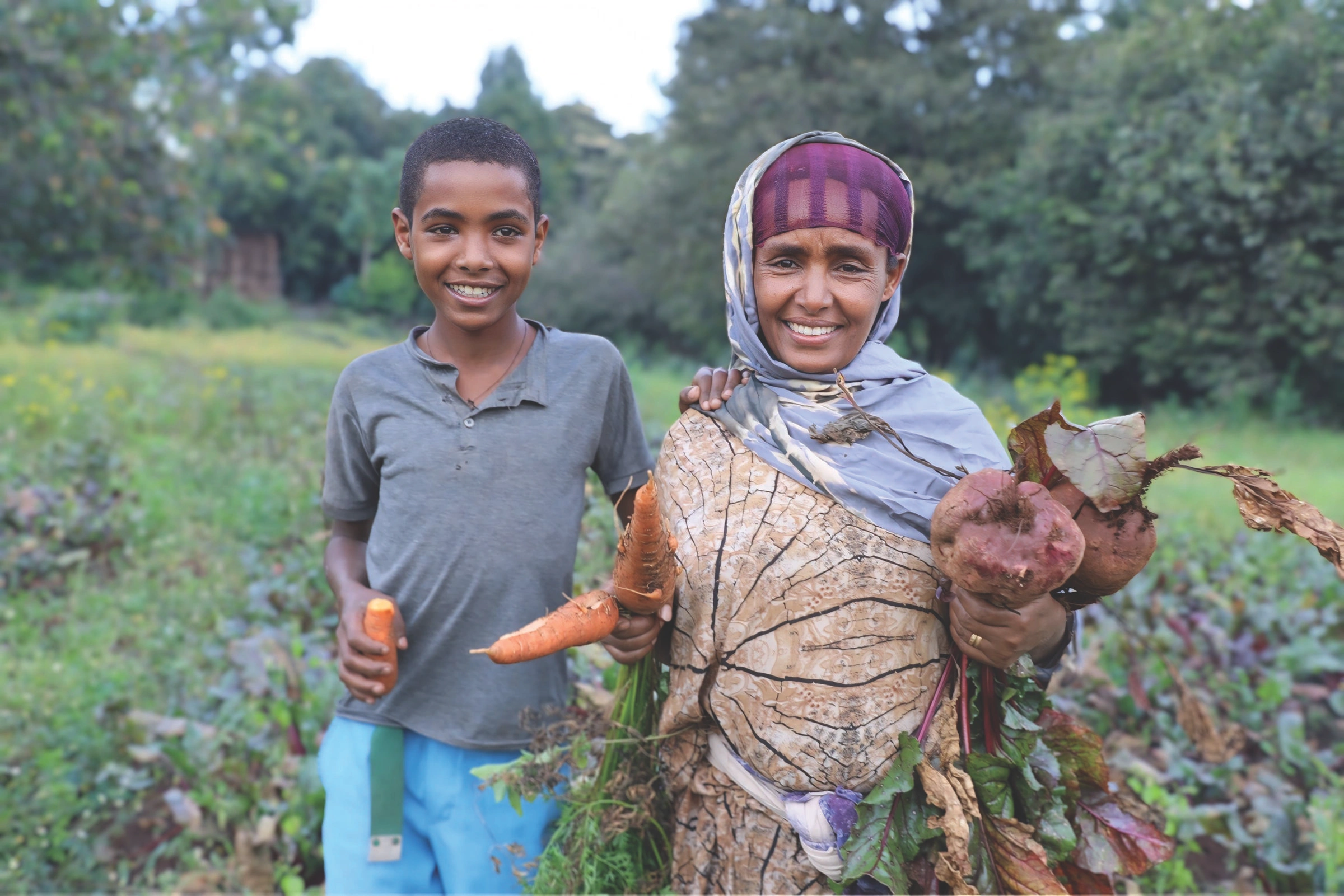 Mother and child showing produce pulled from the garden.