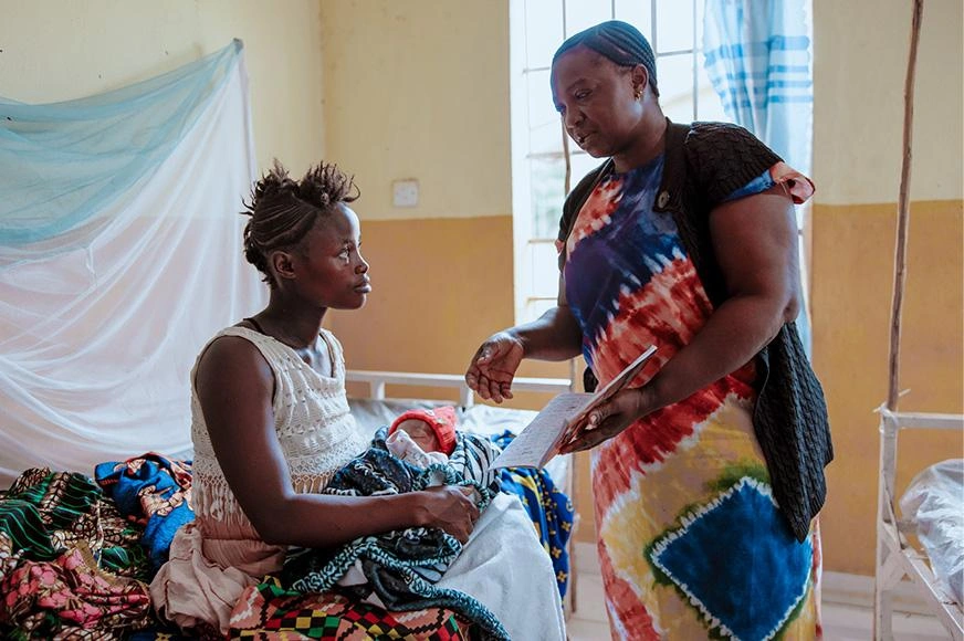 A mother and baby are seen by a healthcare staff in a local clinic.