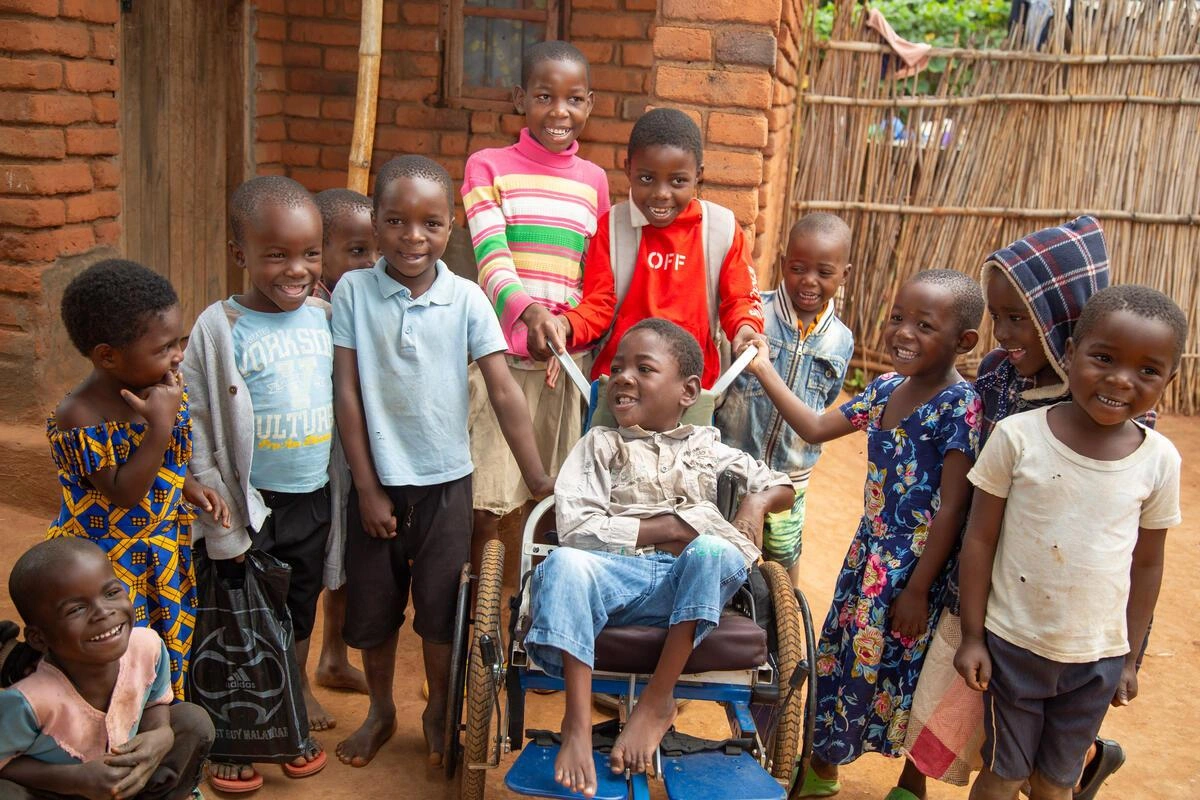 A group of children standing around a child in a wheelchair (Malawi, 2025)