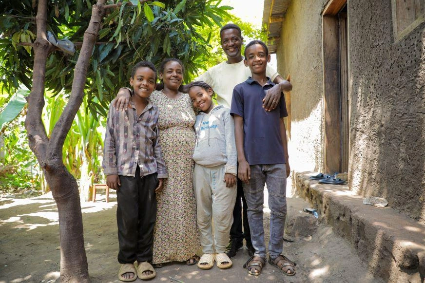 A family of five in southern Ethiopia stands smiling with their arms around each other.