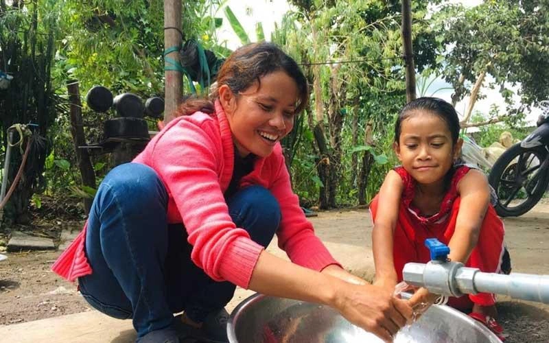 Poverty Reduction - woman helps a girl wash hands