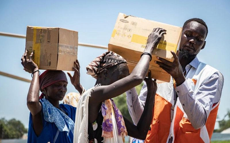 Poverty Reduction - World Vision staff helps carry boxes of food