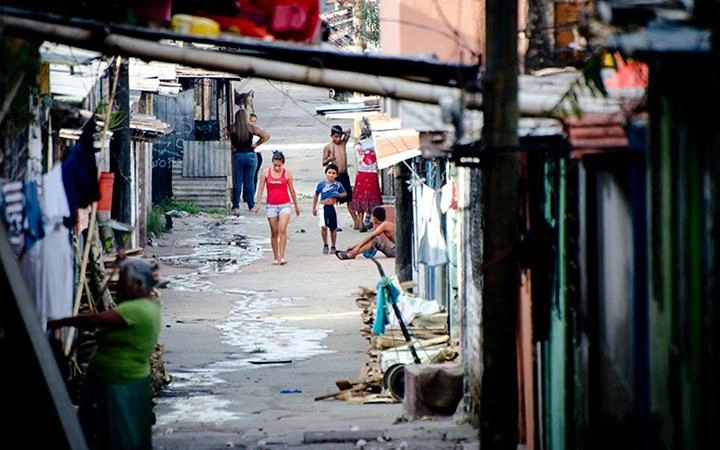 An adolescent girl and younger boy walk down a narrow alleyway together.