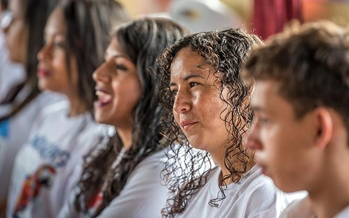 Close-up of a row of five teens or young adults wearing white T-shirts, listening to a workshop held by World Vision.