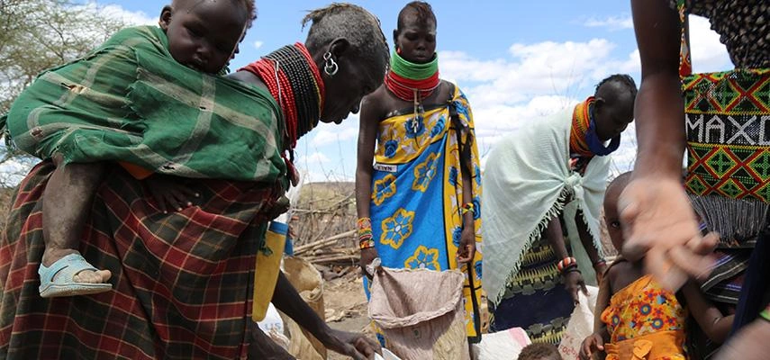 In Kenya, a group of women hold empty food bags, waiting for emergency food.