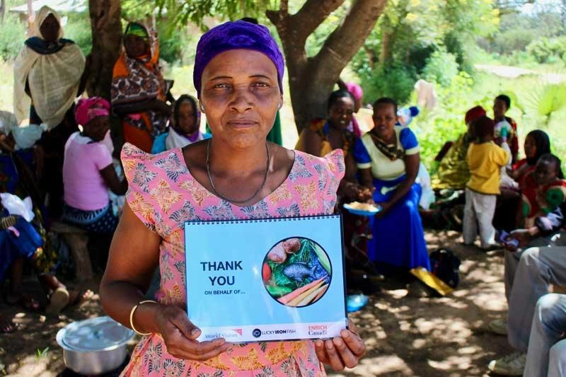 A woman in Tanzania holds a training manual provided by World Vision on how to use the Lucky Iron Fish.