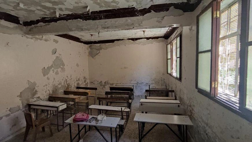 Damaged classroom with broken ceiling and empty desks, showing disruption to education in a conflict-affected area. (Syria, 2022)