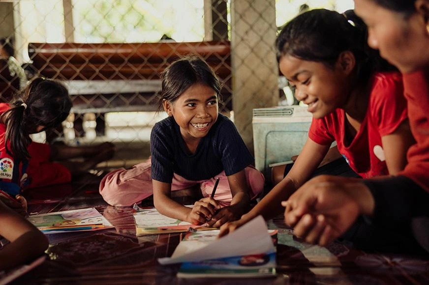  Cambodian girls joyfully read and colour together at a reading program.