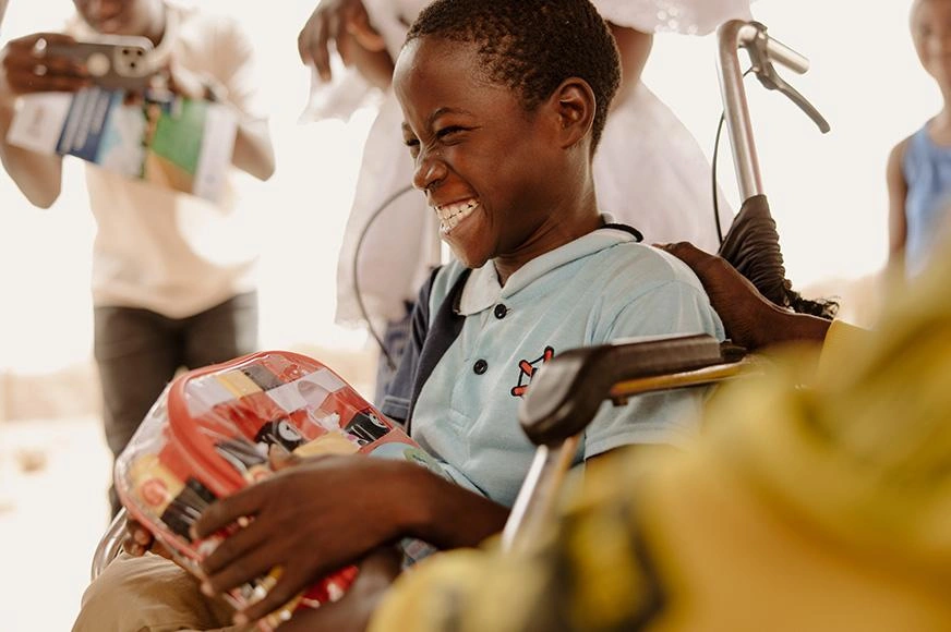 A boy from Senegal beams with joy as he uses his new wheelchair. 