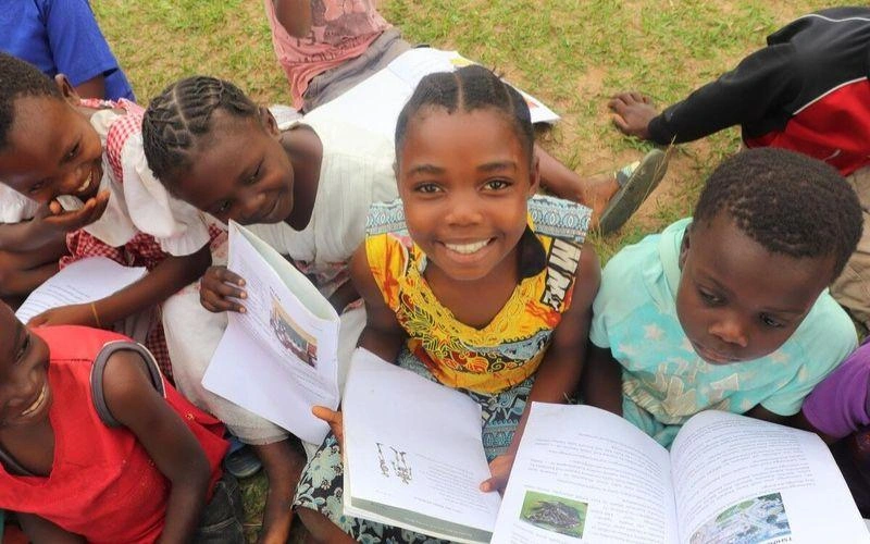 Une fillette est assise au milieu d'un groupe d'enfants qui lisent des livres.