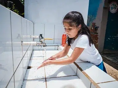 A young girl washes her hands outside of the new latrines supplied by World Vision at a school in Copan Ruinas. (Honduras, 2023)