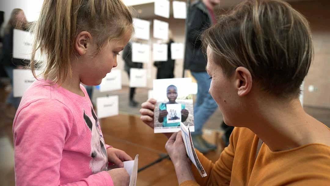 Mother and her young child look at the picture of the girl who chose their family to sponsor her.
