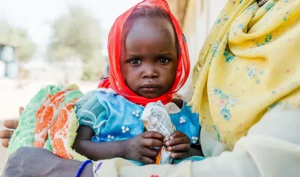 A young girl holds a ready-to-use therapeutic food packet. (Chad, 2025)