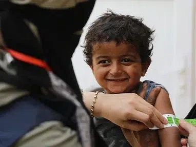 A physician places a mid-upper arm circumference tape measure on a young boy’s arm to see if he has recovered from malnutrition. (Syria, 2023)