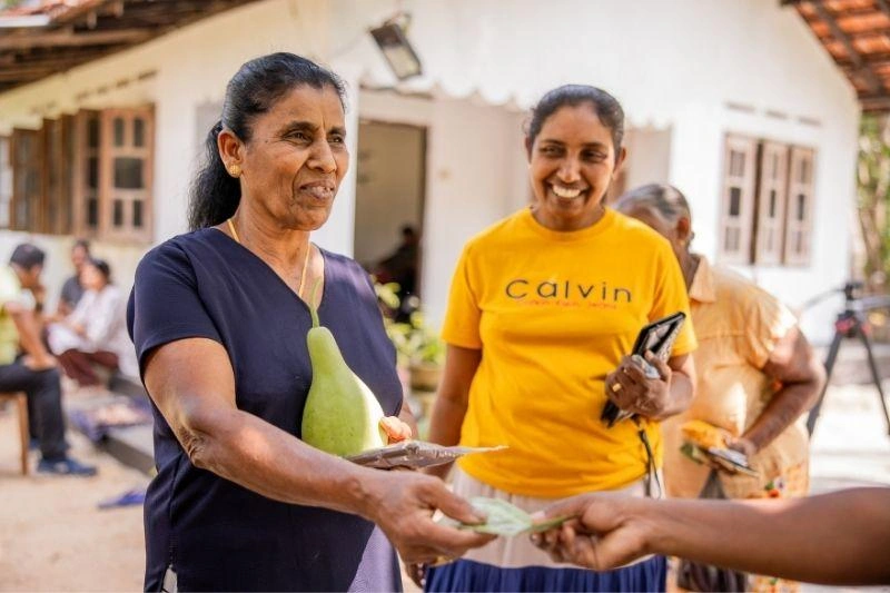 Woman smiles exchanging money in a World Vision savings group.