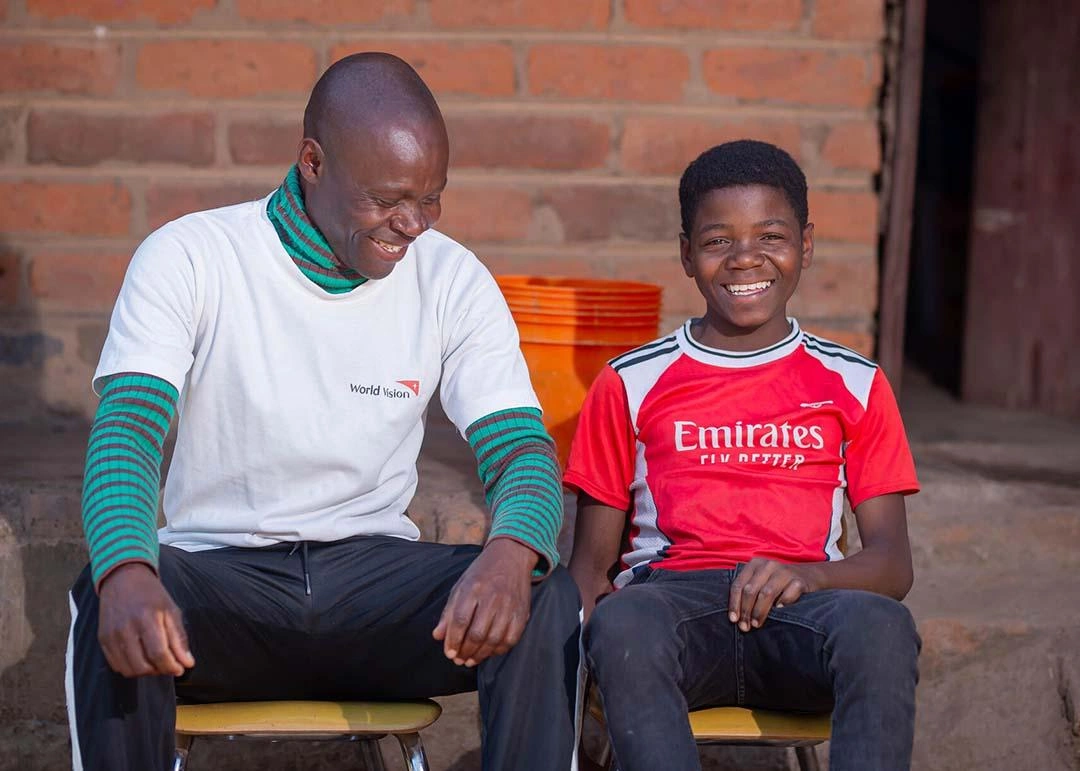 Empowered son and dad sit together and smile.