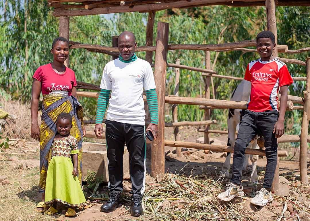 Alabi family proudly stands in front of their pen that holds the cow that produces milf for their family.
