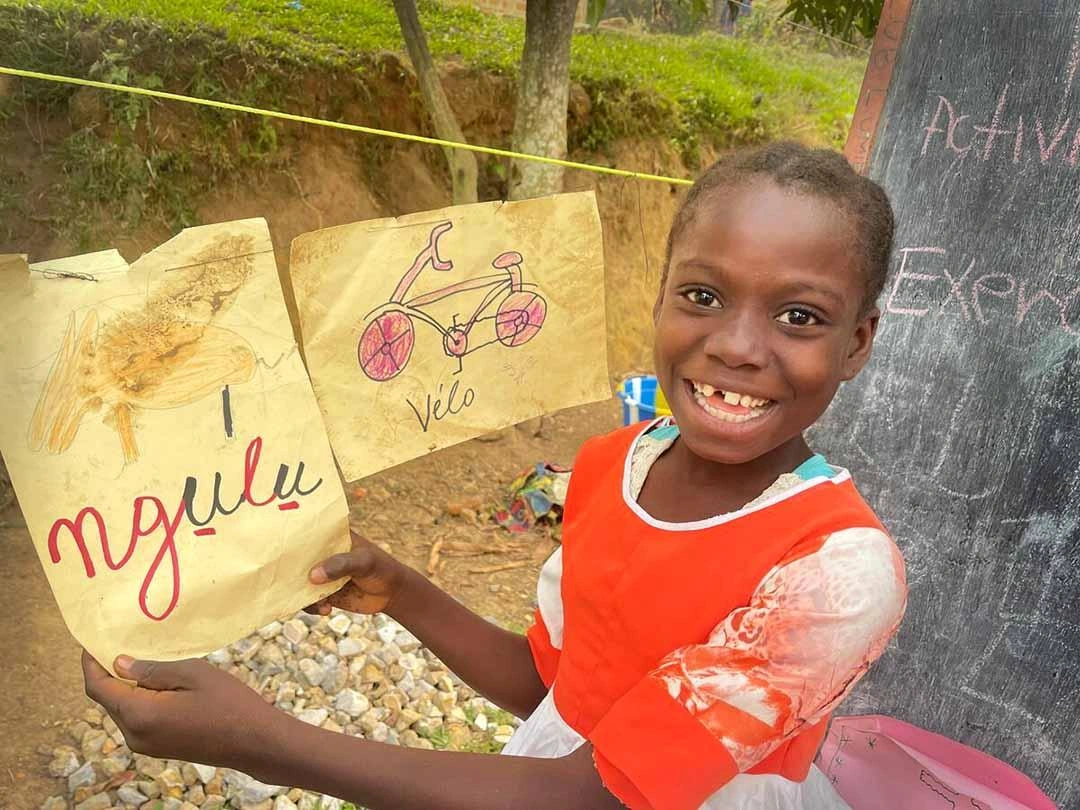 Séverine 9, in the DRC, smiles proudly that she can now read after having difficulties.