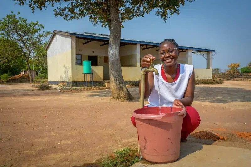 School girl gets clean water from a public tap.