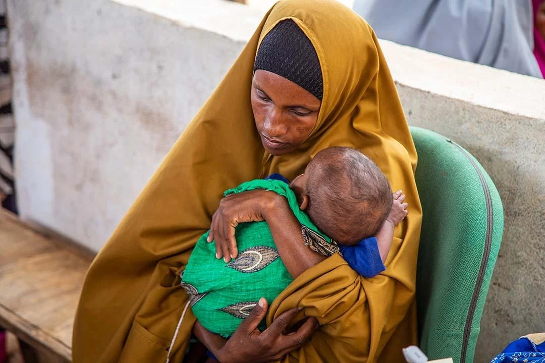 Woman holds small baby close.
