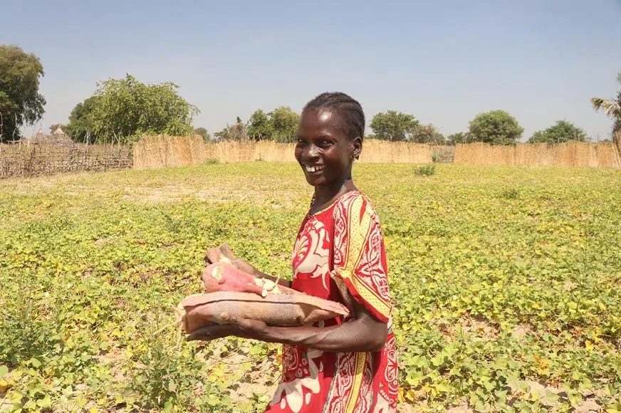 Asunta harvested sweet potatoes she learned how to grow thanks to partnerships with World Vision. (South Sudan, 2022)