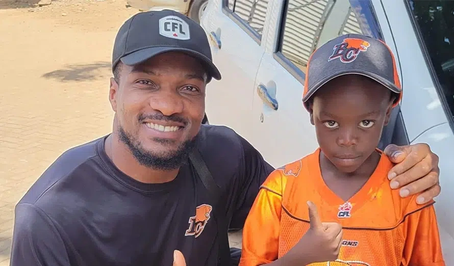 Boseko Lokombo and young boy give a thumbs up in BC Lions shirts and caps. (Kenya, 2024)