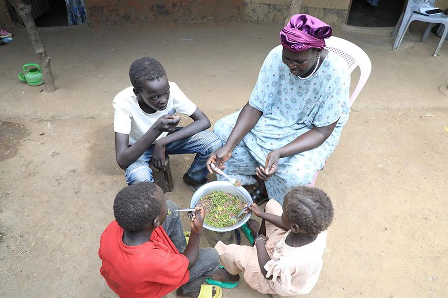 A mother and her three children sit together, sharing a nutritious meal.