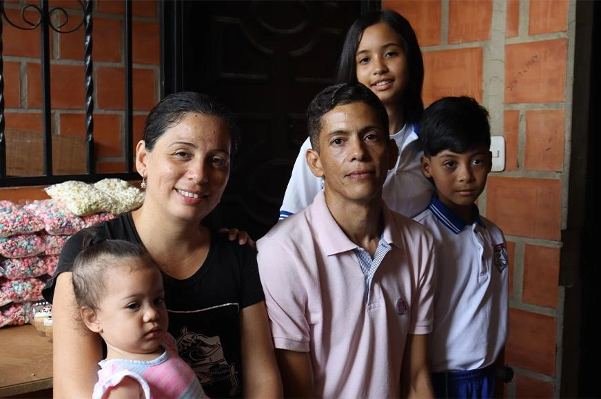 A Venezuelan refugee family pose in front of their food stand.