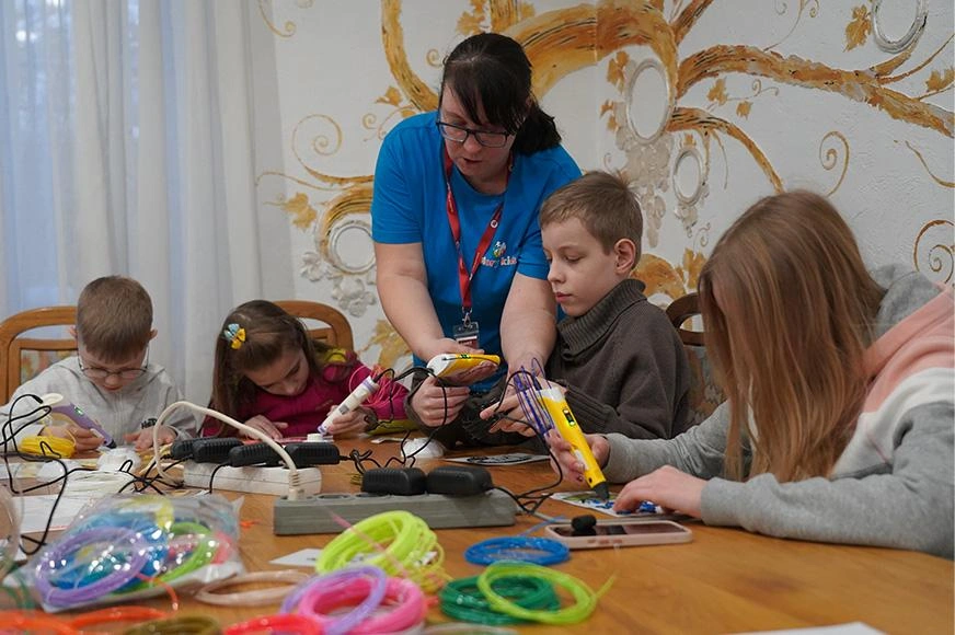 A facilitator leads a group of Ukrainian children in an arts activity at a child-friend space in Kyiv.