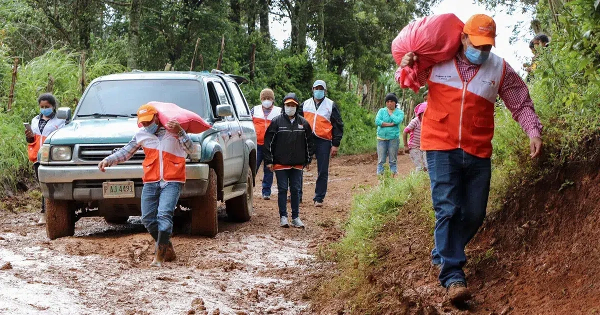 World Vision staff walk along a muddy road in Honduras, delivering comfort kits to a child-friendly space.