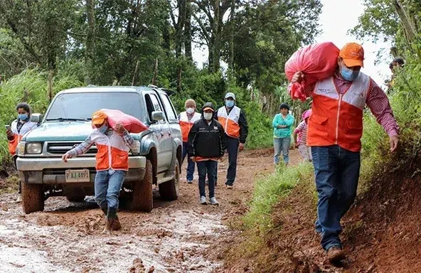 World Vision staff walk along a muddy road in Honduras, delivering comfort kits to a child-friendly space.