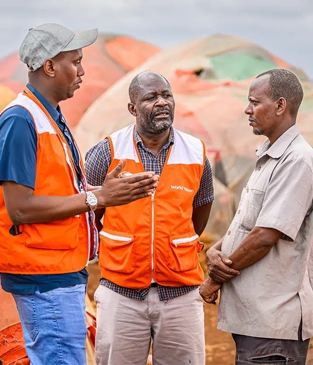 World Vision staff meet with a community member in a temporary settlement to discuss humanitarian support.