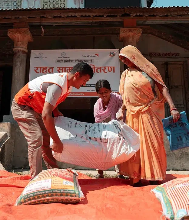 World Vision staff distribute a relief aid package to a woman and a child during an emergency response activity.