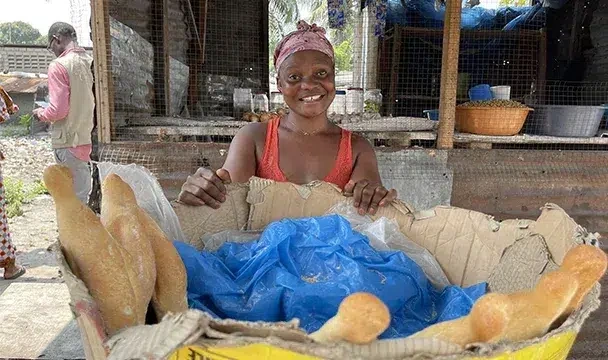 Person behind a cardboard box of bread at an outdoor market stall.