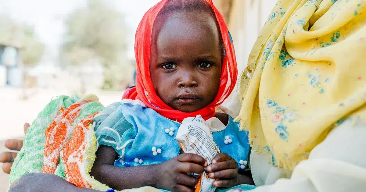 A young girl holds a ready-to-use therapeutic food packet. (Chad, 2025)