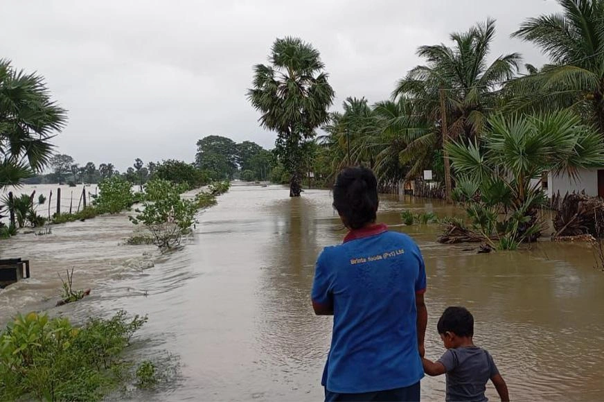 Un fils s’accroche à la main de son père alors qu’ils avancent dans les eaux qui ont envahi les rues après le passage d’un cyclone.