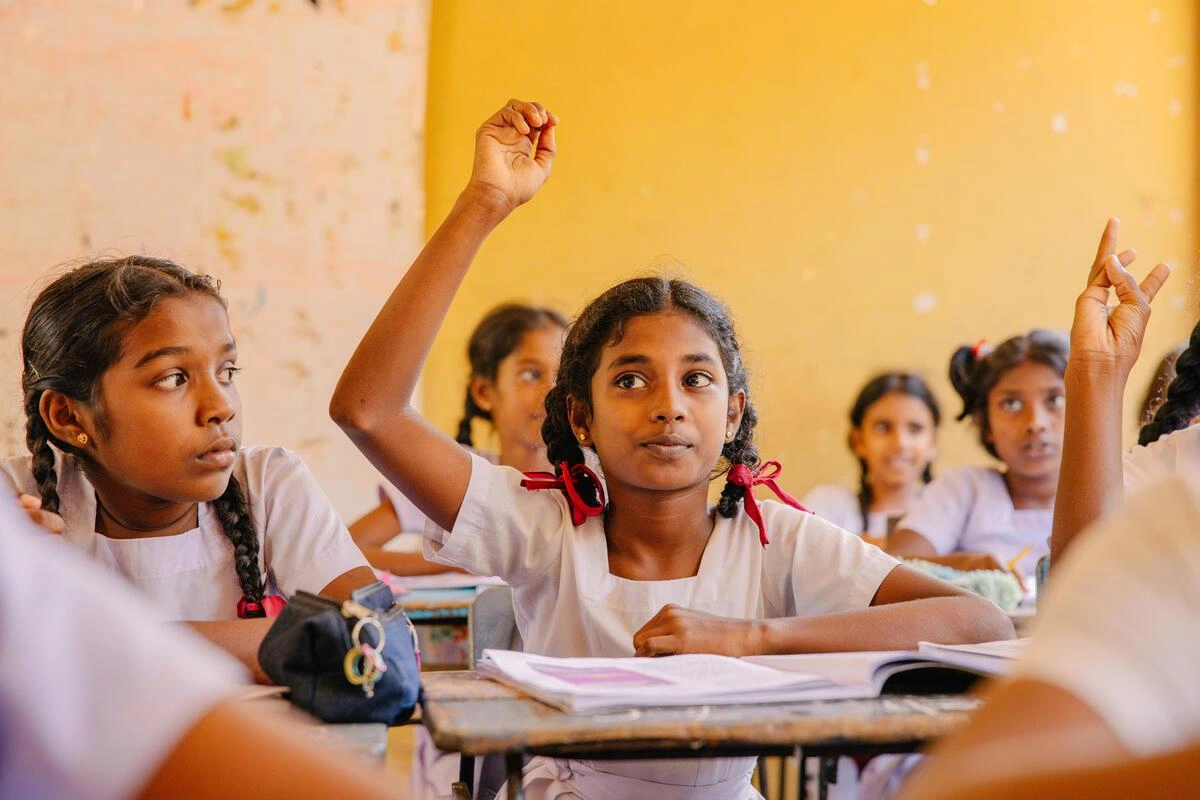Une écolière aux deux tresses lève la main pour répondre à une question. (Sri Lanka, 2025)