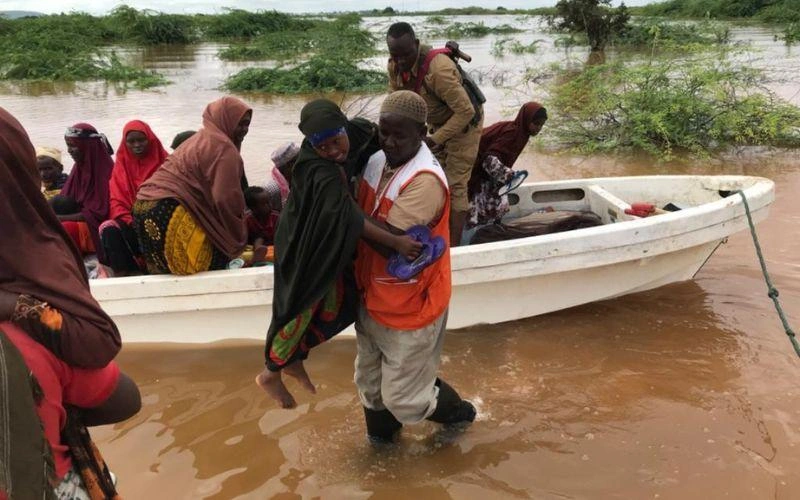 Un homme soulève une femme d'un petit bateau flottant sur les eaux de crue pour l'emmener en terrain surélevé.