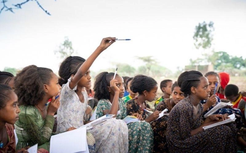 Des élèves éthiopiens sont assis dehors, leurs cahiers d'école à la main.