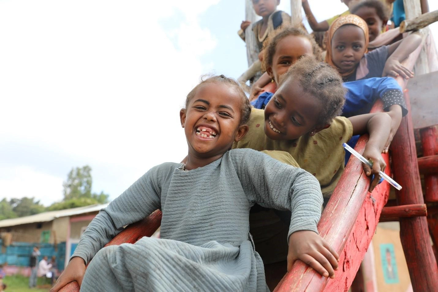 Un groupe d'enfants sourit sur un toboggan.
