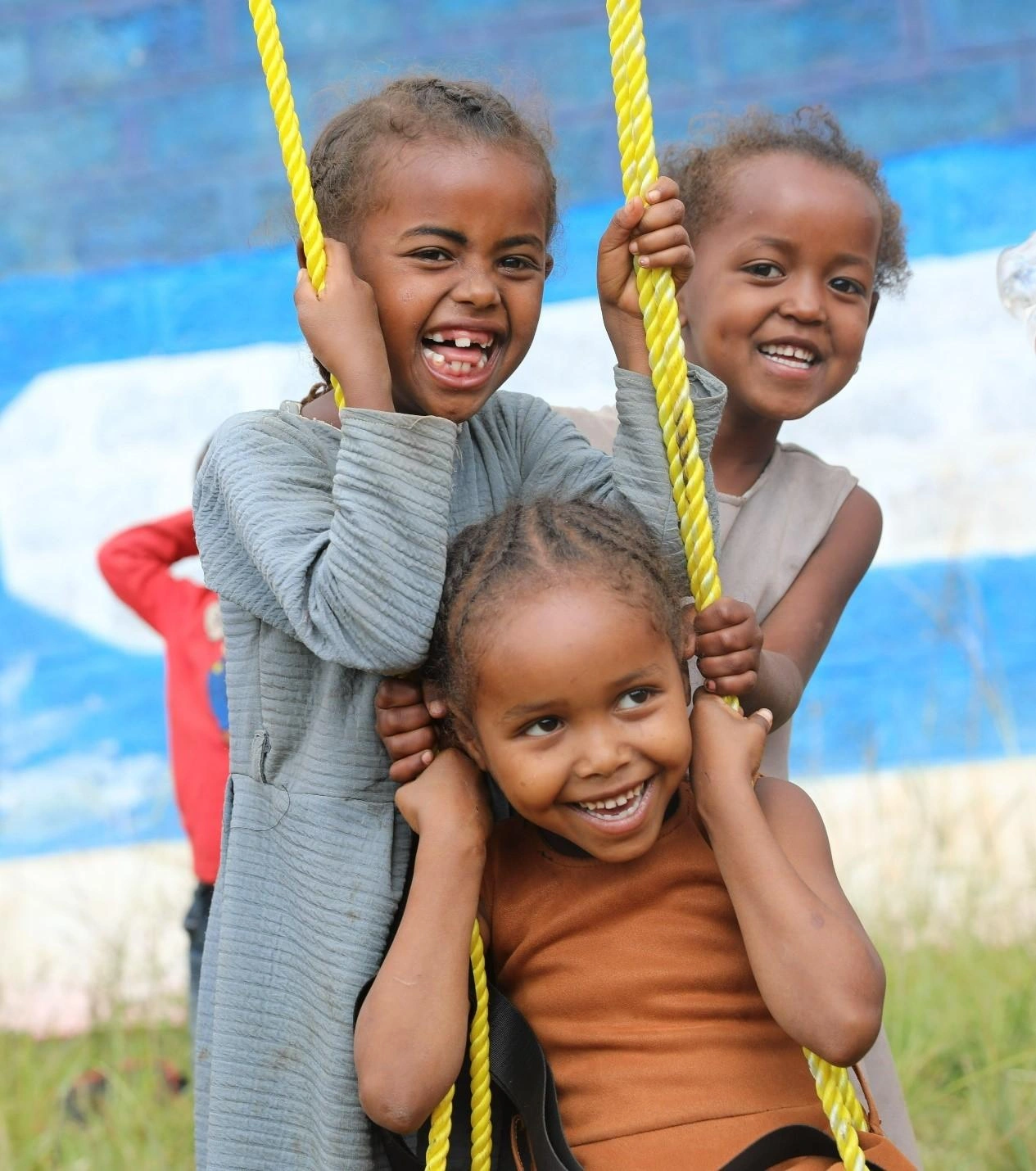 Un groupe d'enfants sourit sur une balançoire.