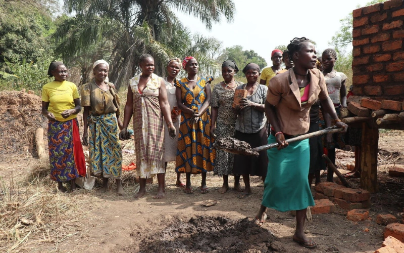 Mikelina pellete un tas de terre, sous le regard souriant des femmes de son groupe d'agricultrices.